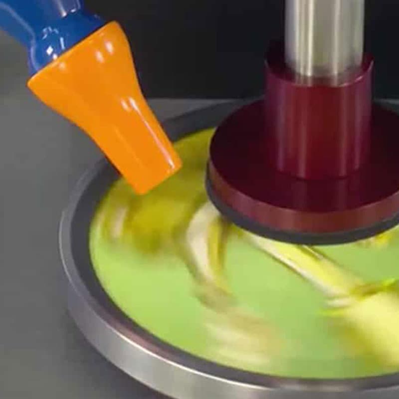 Close-up of the Hanatek RT4 machine in action – The abrasion tester is rotating a material sample, with an orange air nozzle positioned nearby to aid in the process.
