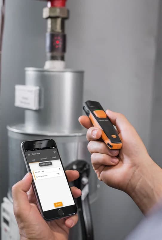 Testo 805i in use measuring temperature of a pipe, with results displayed on connected smartphone.