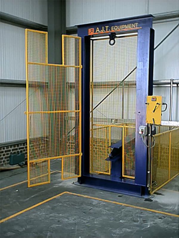 Dynamic block tester with open yellow mesh door revealing internal hoist mechanism, inside safety-zoned area.