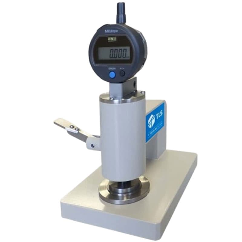 Compression testing device with a cylindrical design, Mitutoyo display, and lever mechanism, showing the TLS logo.