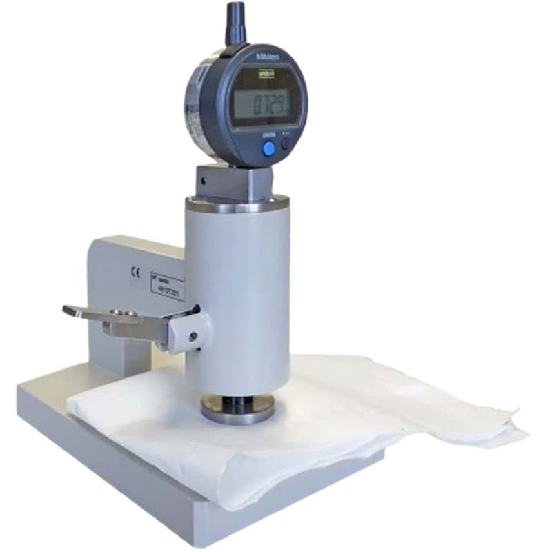 Compact compression tester measuring white material, with a Mitutoyo digital display, lever mechanism, and TLS logo.