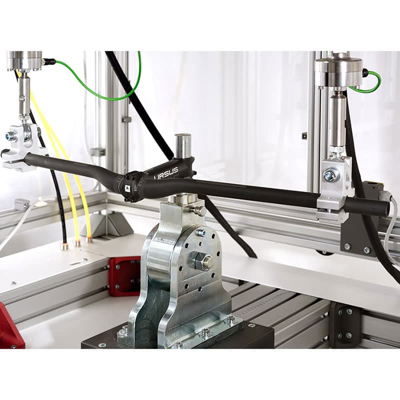 Bicycle handlebar mounted in LiTeM BYC 200 modular fatigue testing machine with actuators applying cyclic load for durability testing.
