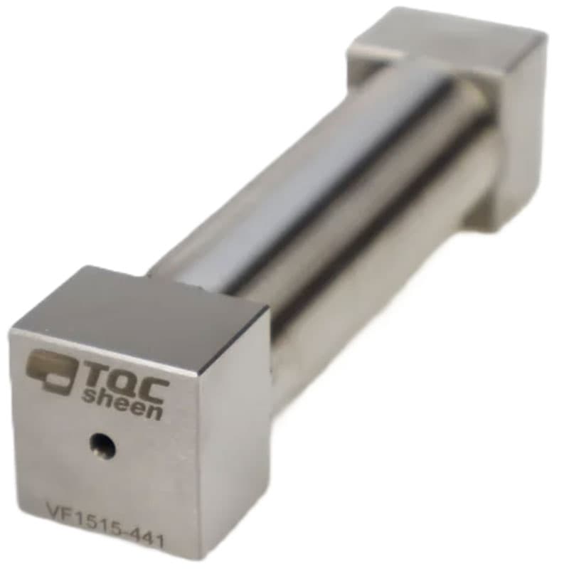 Close-up of a TQC Sheen cylindrical instrument with a polished finish, showing the engraved logo and a central hole on one square end.