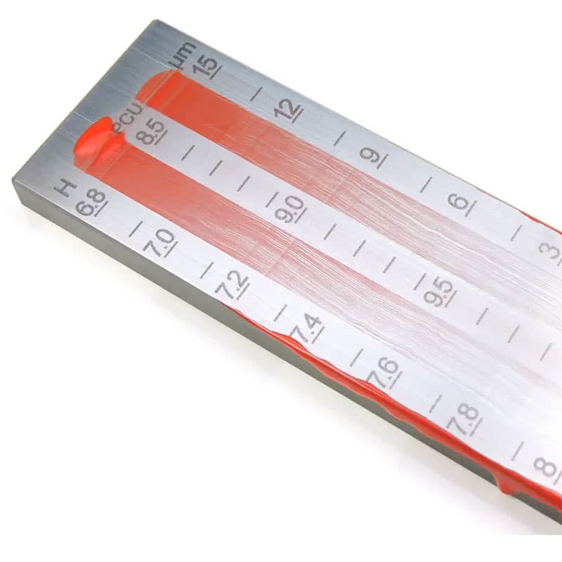 TQC Sheen wet film thickness gauge with red paint coating spread across its measurement scales, ready for thickness evaluation.