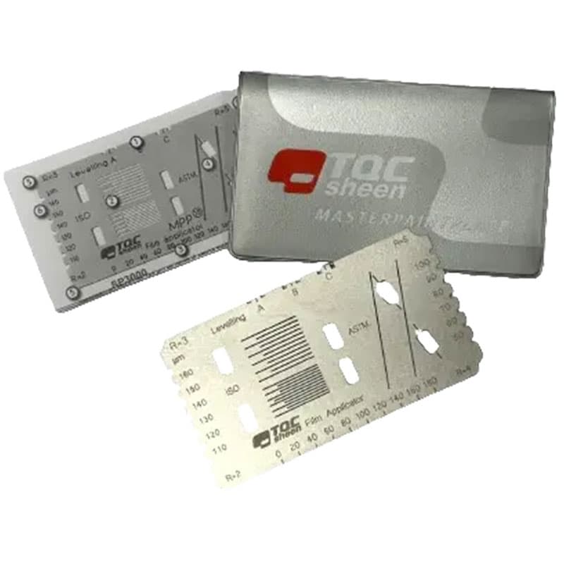 Close-up of TQC Sheen metal templates with calibration marks and a silver storage wallet for paint application and measurement.