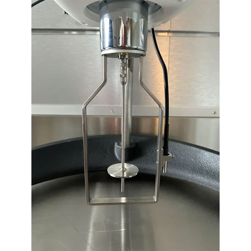 Close-up of a digital viscometer’s spindle attachment, featuring a stainless steel spindle and protective frame over a metallic container.