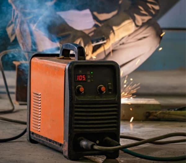 Portable inverter welding machine in use during welding.