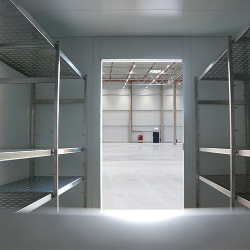 Interior of Binder stability chamber with metal shelves and an open door leading to a large industrial hall.