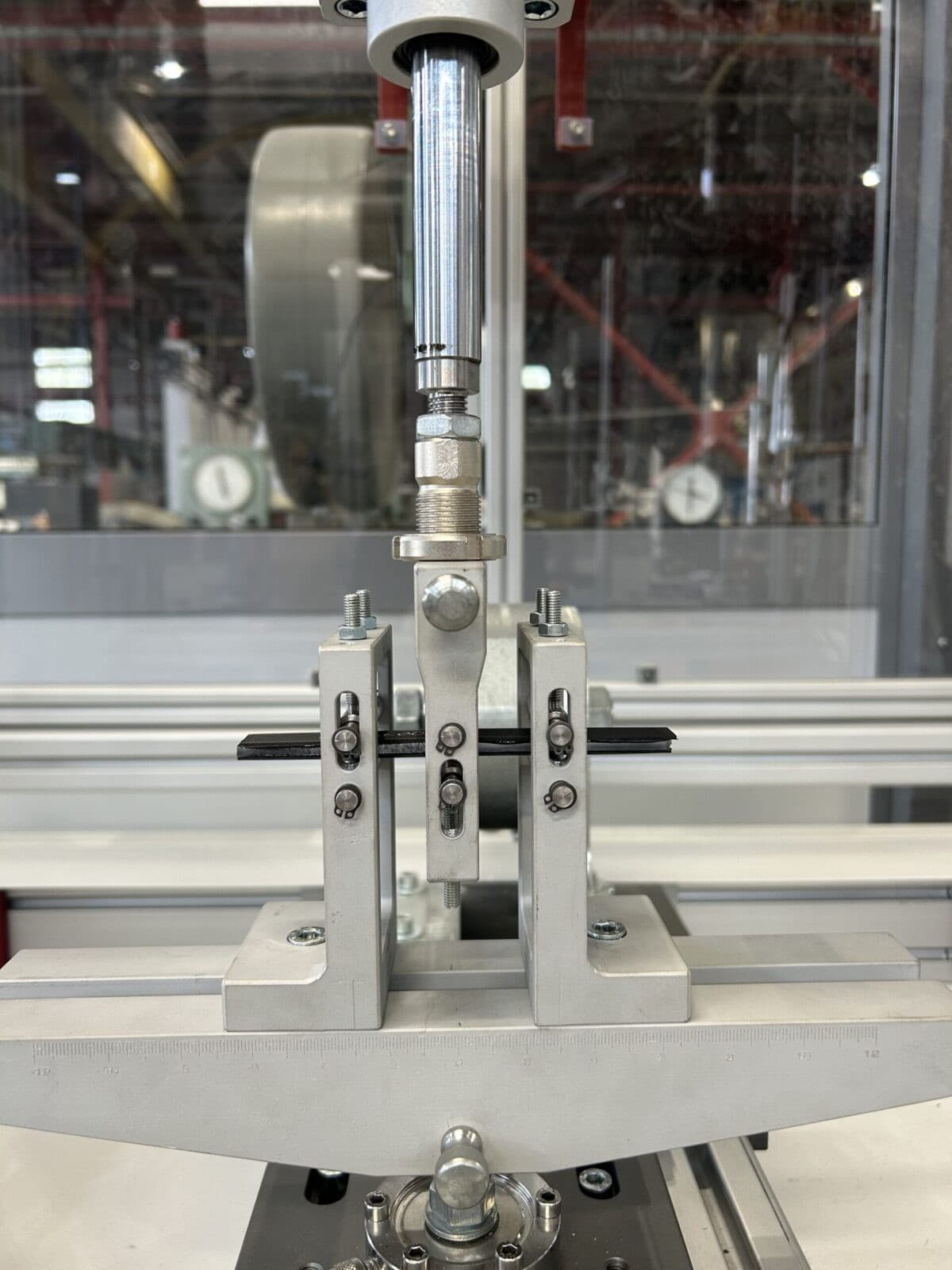 Mechanical testing setup with specimen clamped in grips for adhesion or fatigue testing.