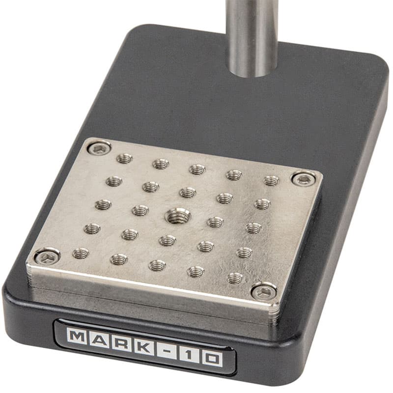 Close-up of the Mark-10 ES05 force test stand base with multi-hole threaded mounting plate for grips and test fixtures.