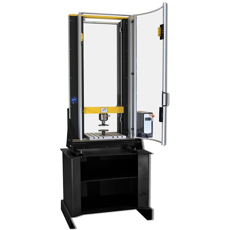 Front view of the SYNTAX 12 Universal Testing Machine – 12 kN with compression platens, open transparent safety enclosure, digital controller, and freestanding base.