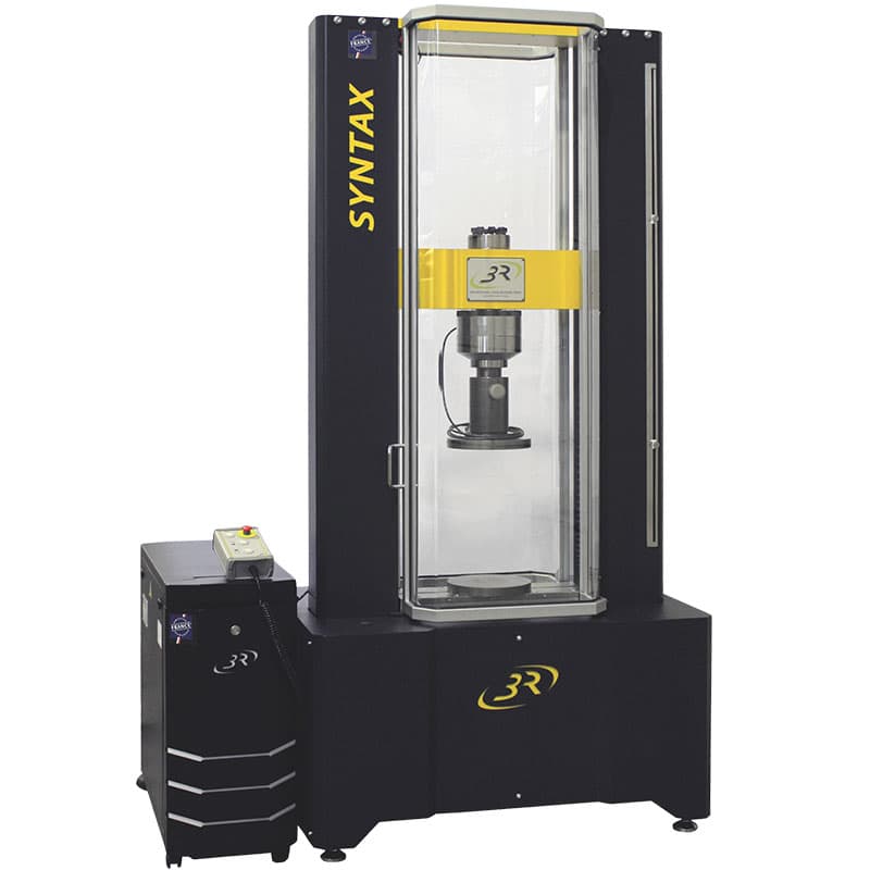 Front view of the SYNTAX 300 Heavy-Duty Universal Testing Machine – 300 kN with dual-column frame, compression fixture, safety enclosure, and control unit.