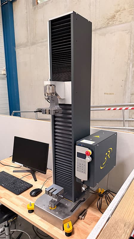 Three-quarter view of the SYNTAX 5 compact 5 kN universal testing machine and side-mounted controller.