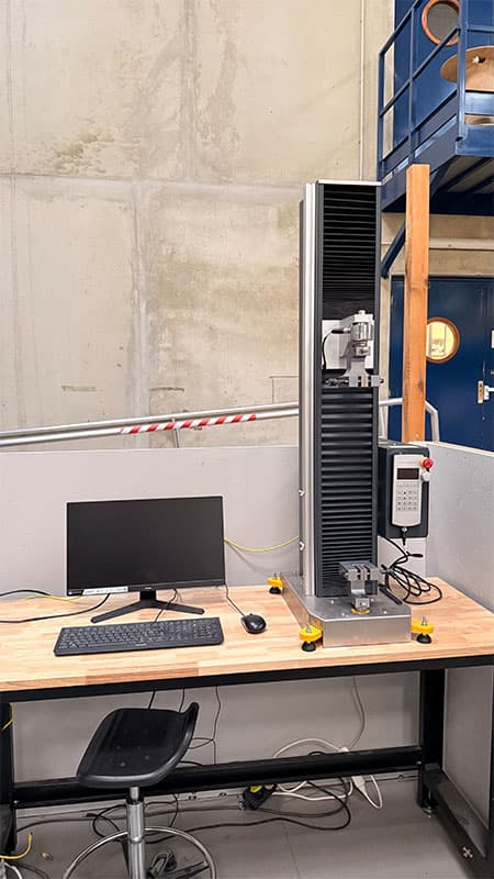 SYNTAX 5 compact 5 kN universal testing machine and computer workstation in a laboratory.