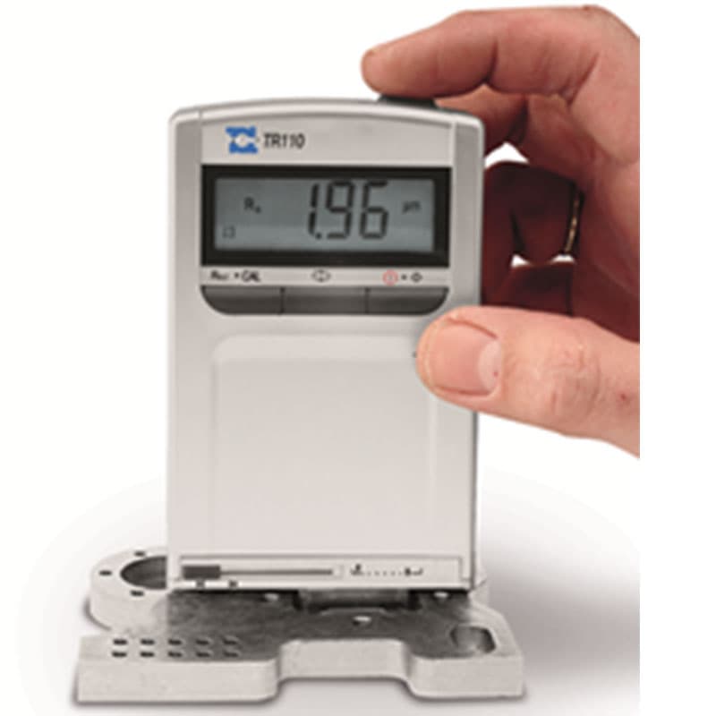 TR110 handheld digital surface roughness tester measuring a metal surface, with LCD displaying a roughness reading of 1.96 µm.