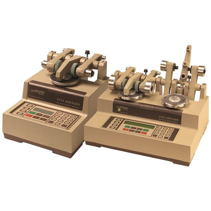 TABER Rotary Platform Abraser with rotating specimen platforms, abrasive wheel assemblies, and digital control panels for material abrasion and wear testing.
