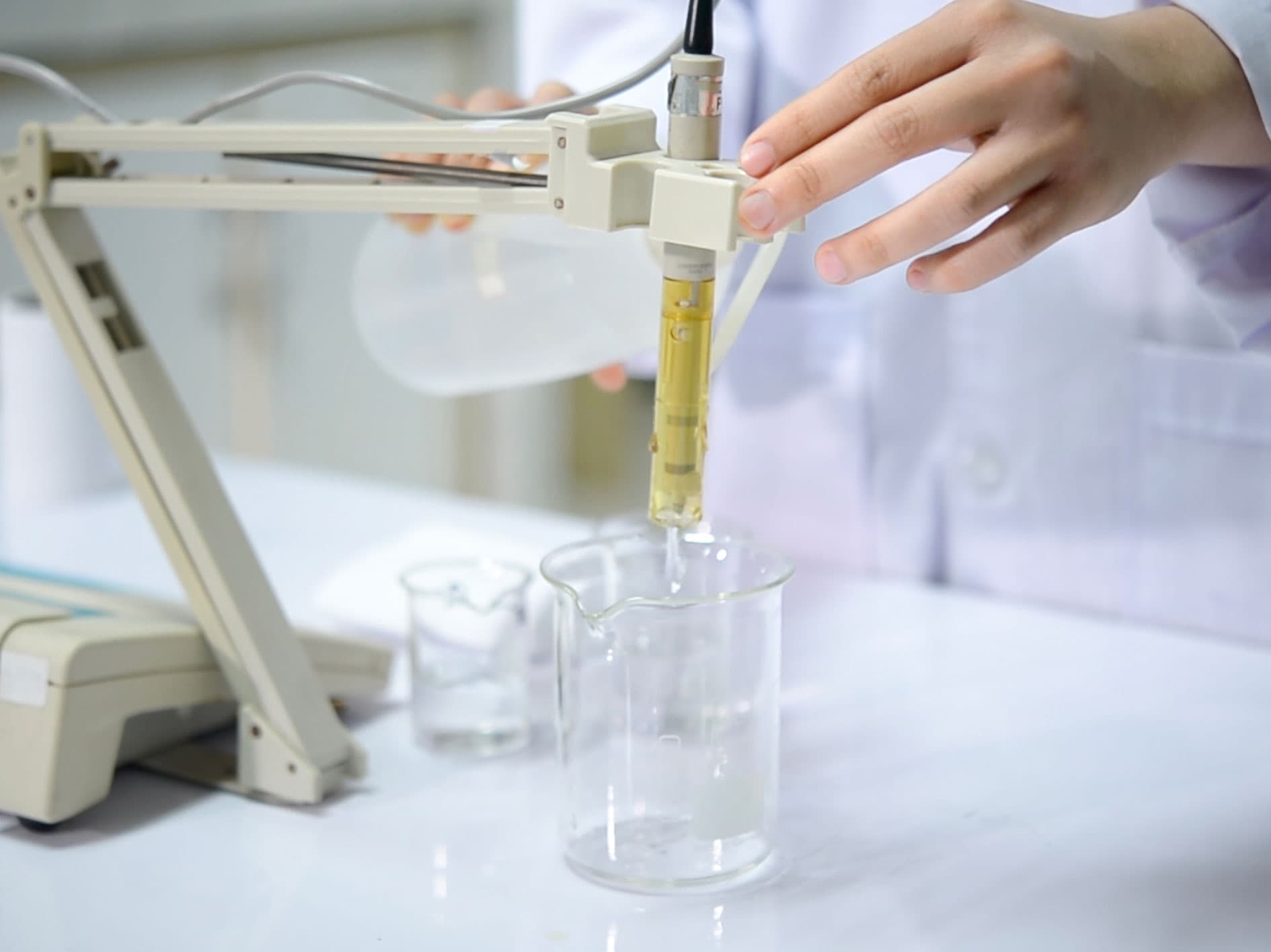 Scientist measuring pH levels of a liquid sample in a laboratory using a digital pH meter.