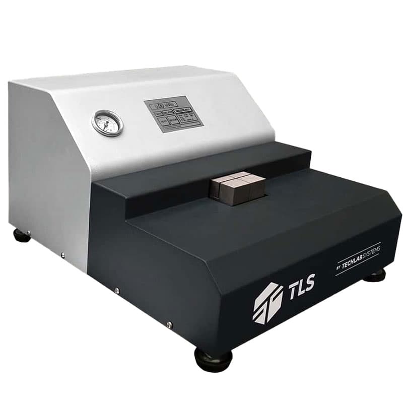 TechLab Systems (TLS) S-TEST testing machine with a digital control panel, pressure gauge, and a metallic testing block on the platform."