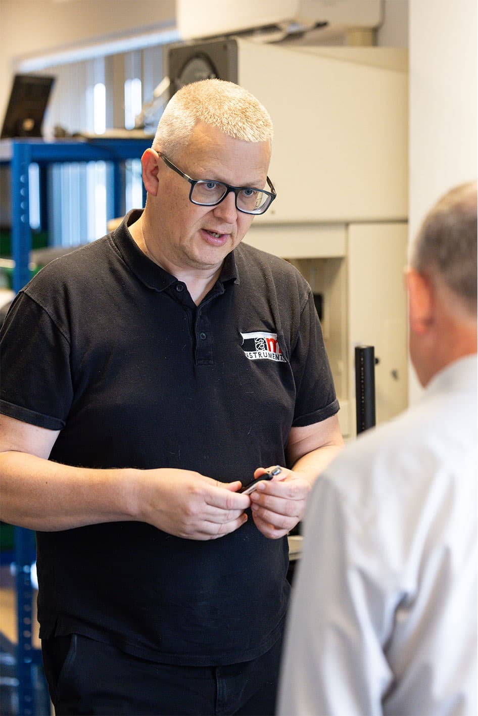 AML Instruments Managing Director Alex Leeson explaining a small component and offering calibration advice to a local business owner.