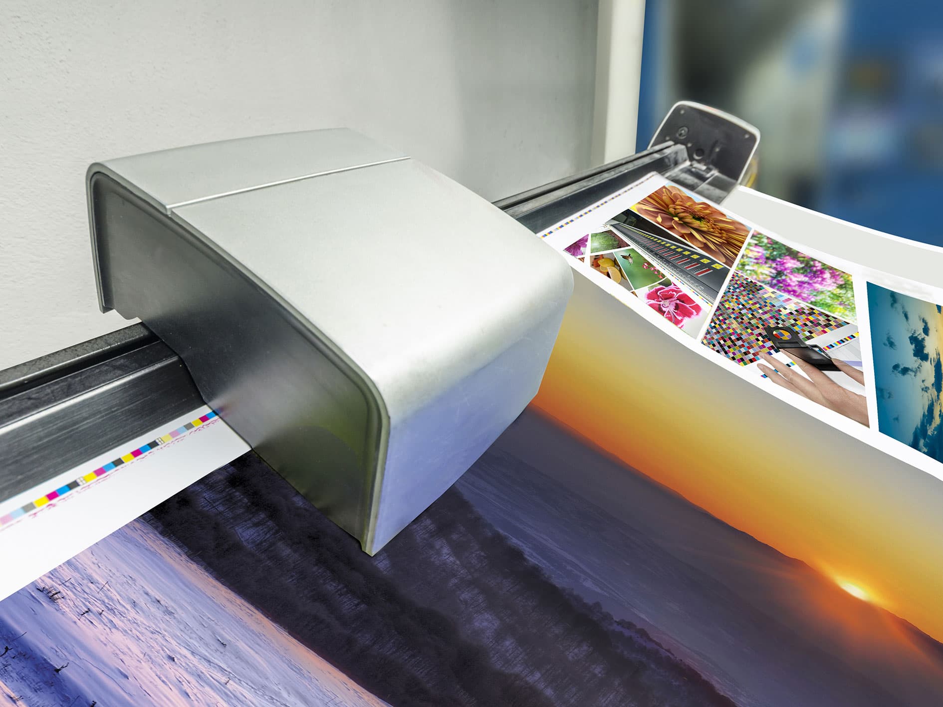 Inline color measurement device scanning prints with colour control strips from a large-format printer.