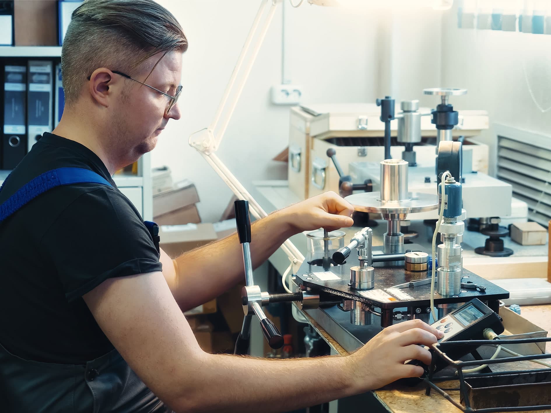 Technician operating a lab testing machine and adjusting controls during calibration.