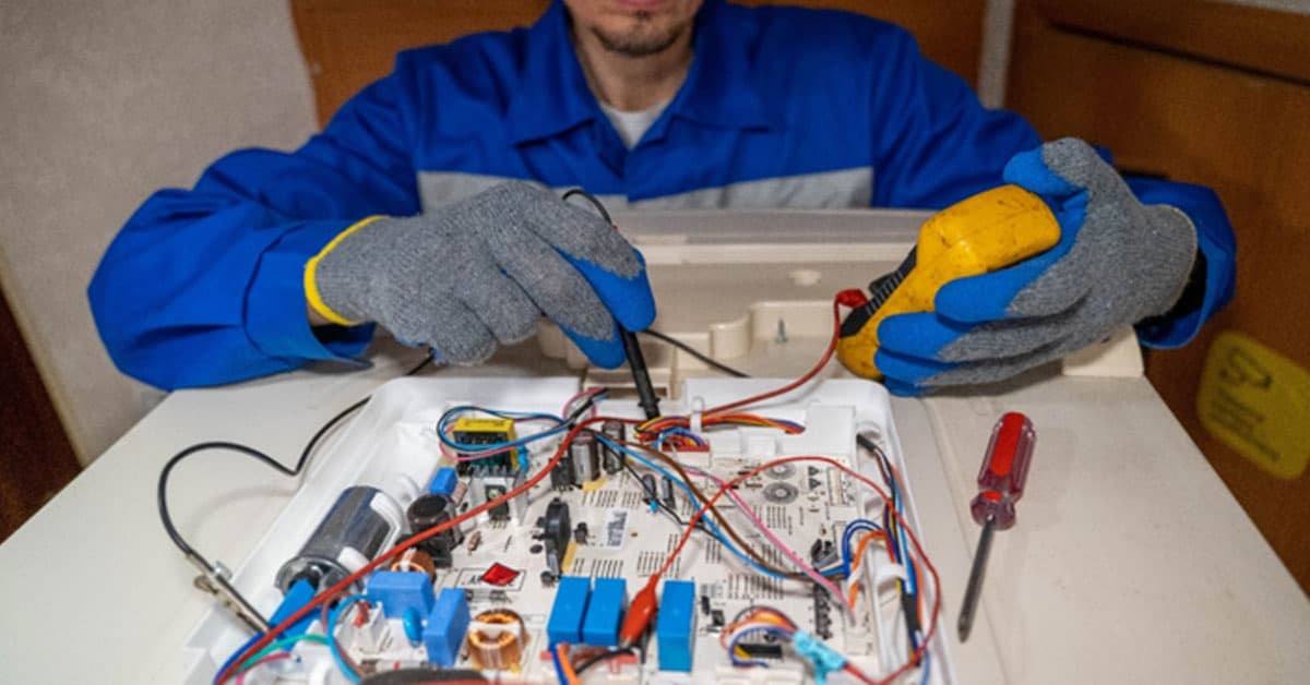 Technician using a handheld tester to check wiring on an open electronic device.