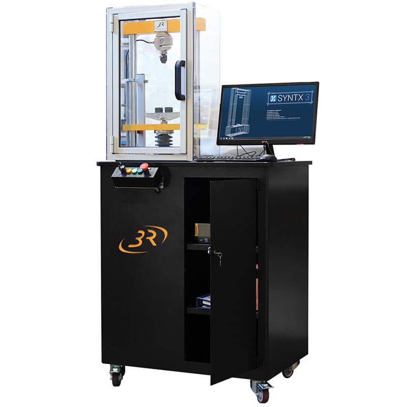 Angled view of the SYNTHON 25 kN Teaching Universal Testing Machine with transparent safety enclosure, integrated computer, monitor, and mobile workstation.