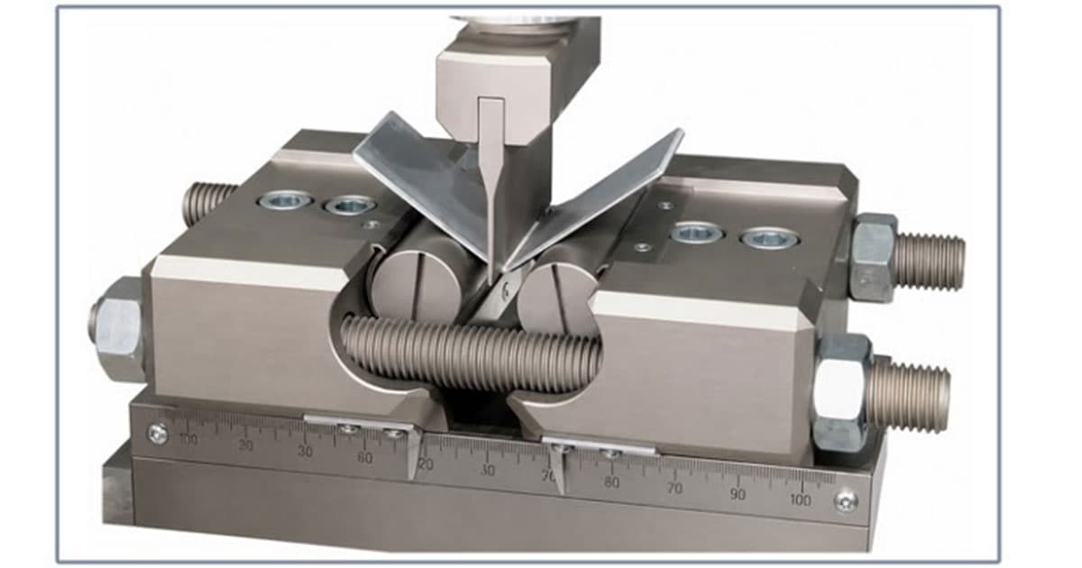 Close-up of a TH22 VDA238 bend fixture testing a sheet-metal specimen between two support rollers.