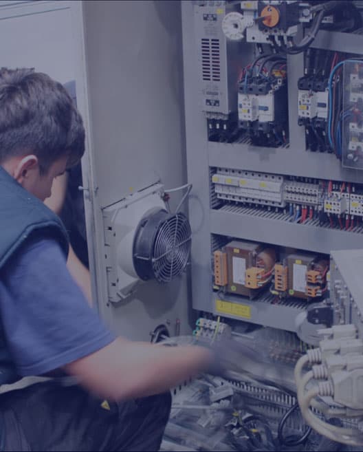 Engineer upgrading electrical controls and wiring inside a test machine cabinet during a modernisation retrofit.